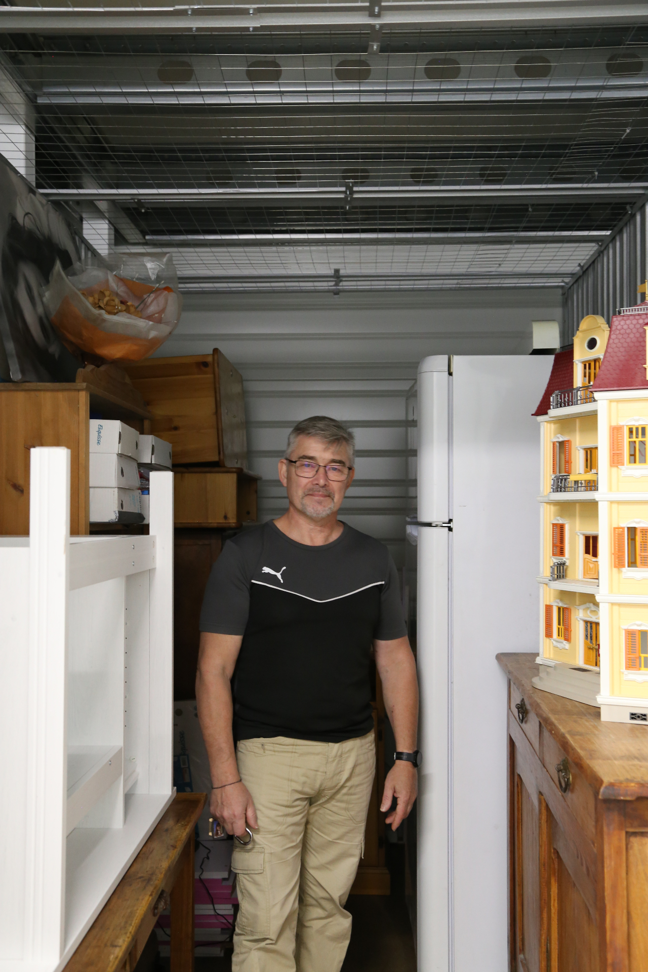 Client souriant dans son box de stockage rempli d'affaires